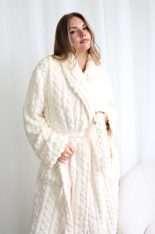 Woman wearing a white textured robe against a plain background