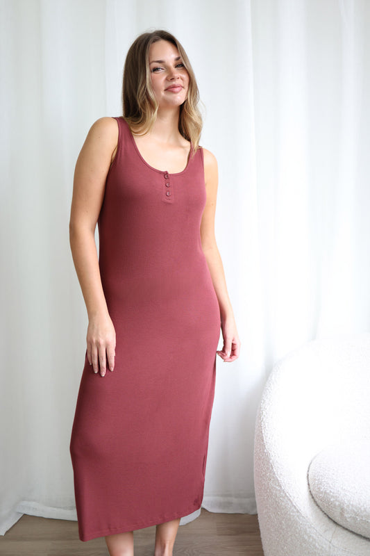 Woman wearing a maroon sleeveless dress against a white curtain background