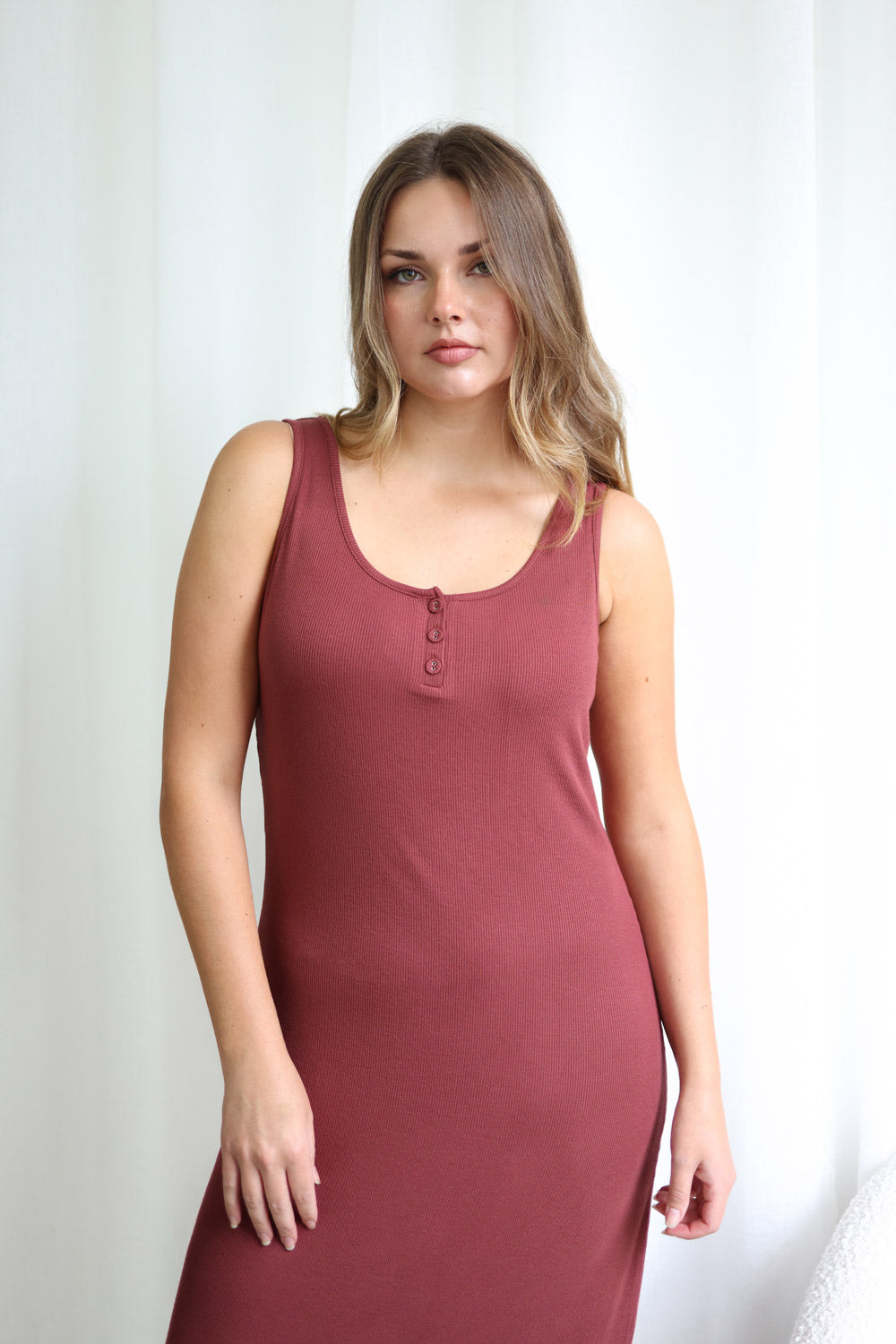 Woman wearing a burgundy sleeveless dress against a white background