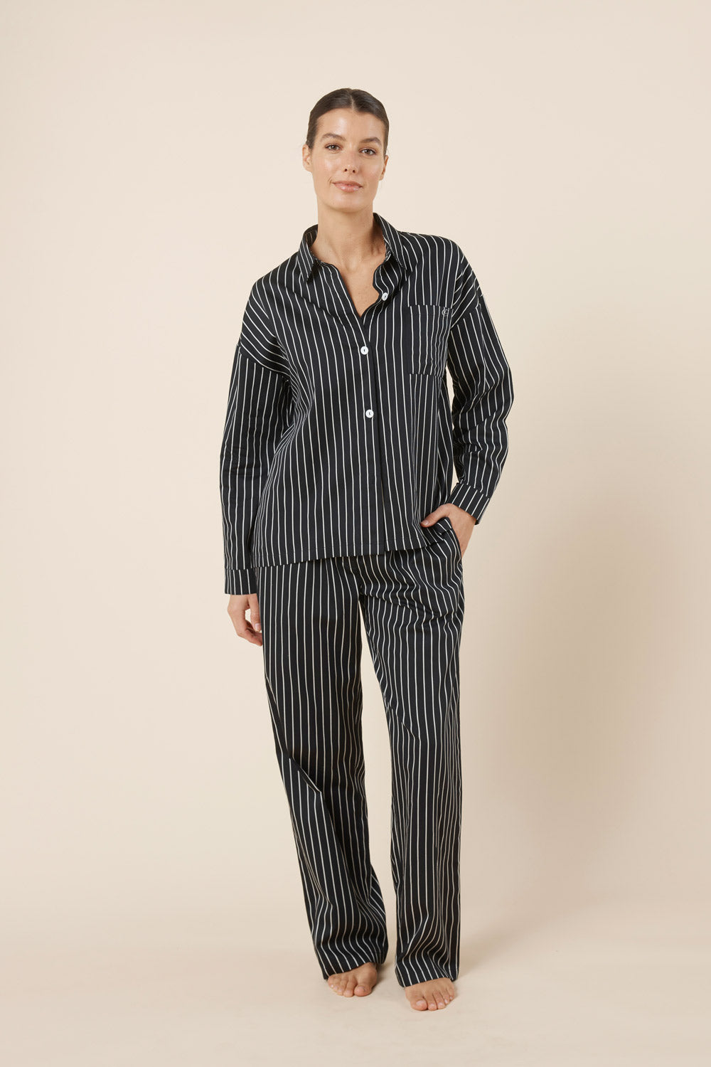 Woman wearing a black and white striped pajama set on a beige background