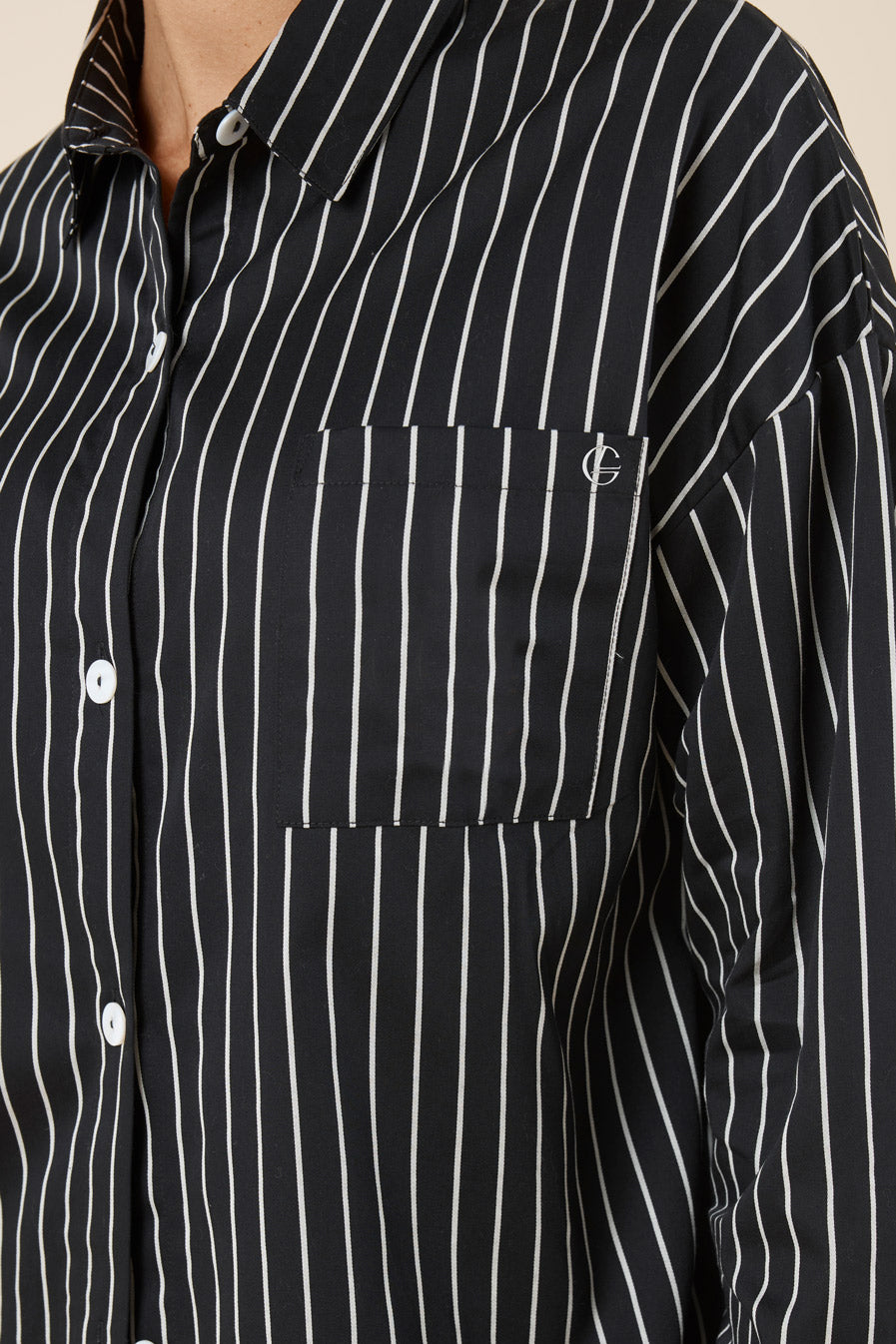 Black and white striped shirt with a brand logo on a beige background