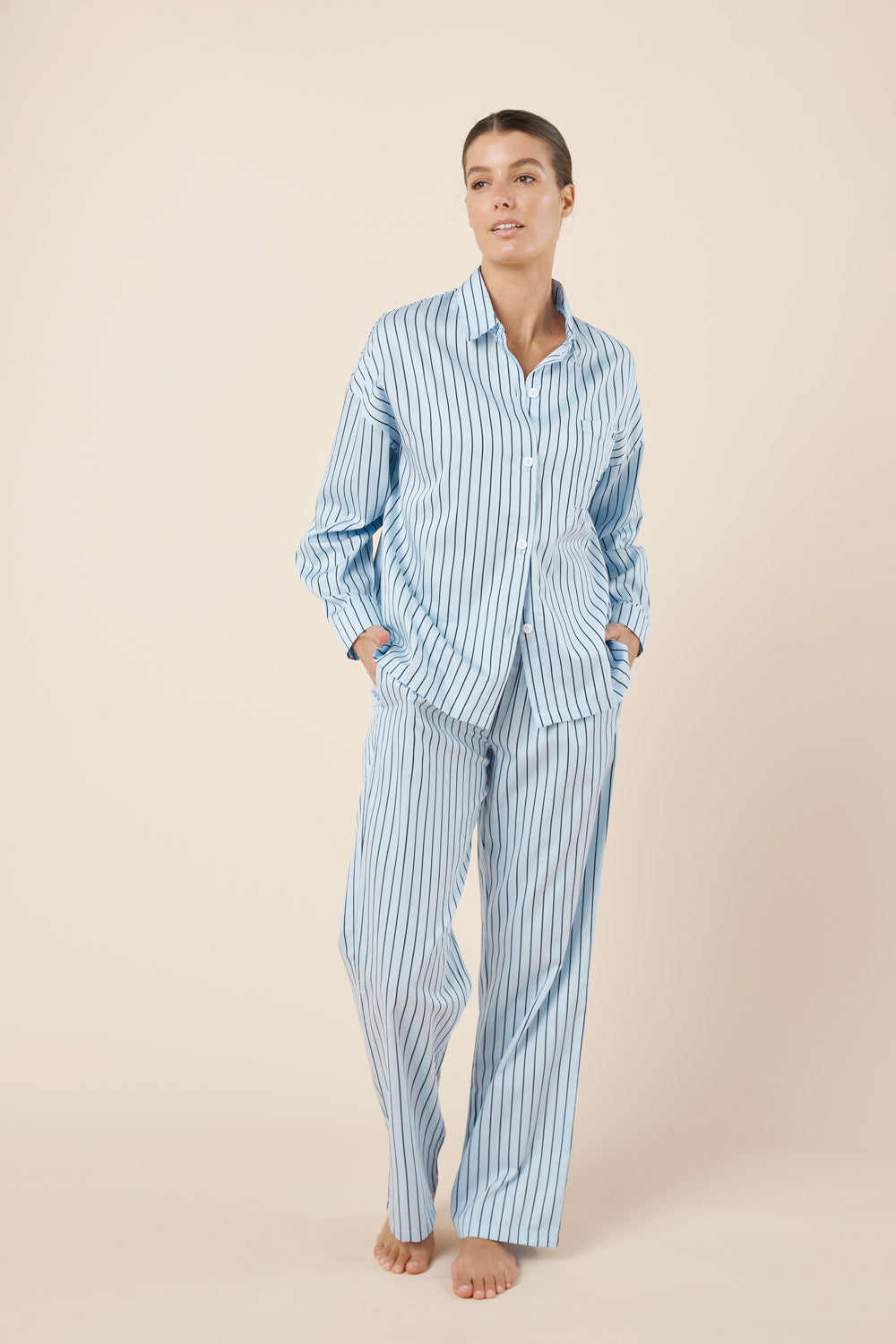Woman wearing a blue striped pajama set on a beige background