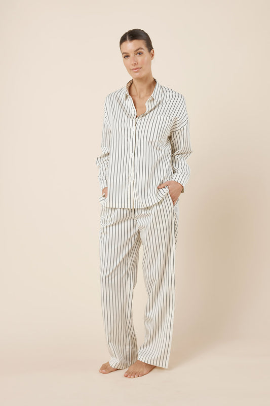 Woman wearing a striped pajama set on a beige background