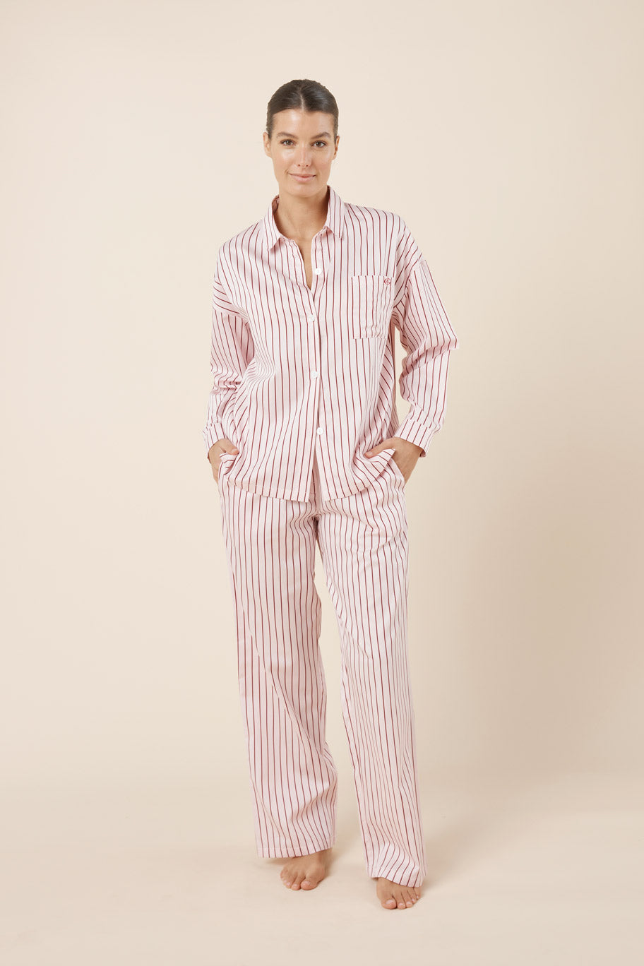 Woman wearing a red and white striped pajama set on a beige background