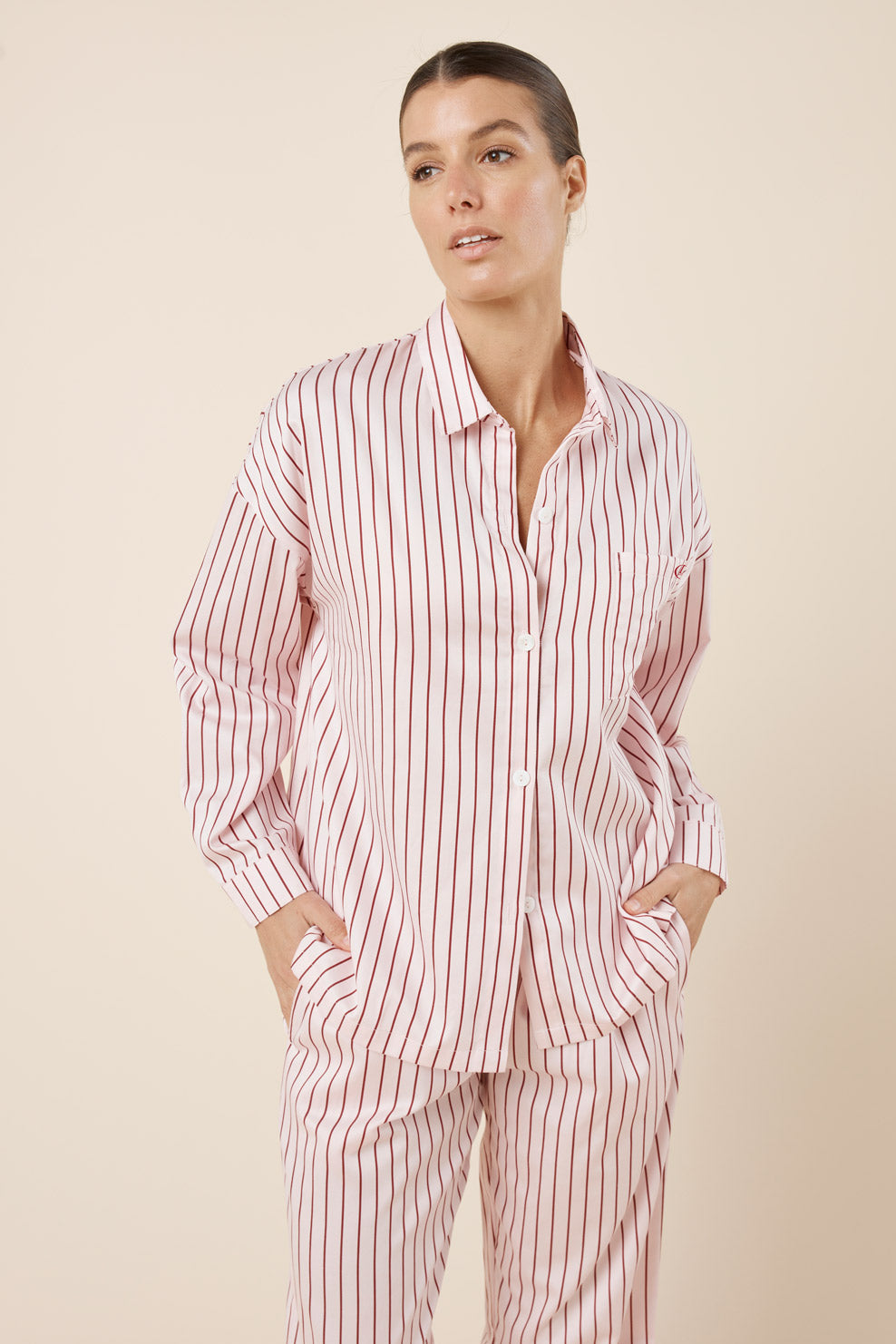 Woman wearing a pink and white striped pajama set against a beige background