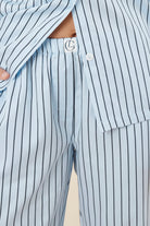 Woman wearing a blue striped willow cotton stripe pyjama PJ set with close up of waistline showing gingerlilly logo and white buttons