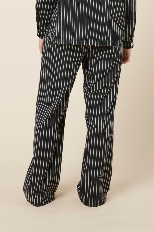 Person wearing Willow Cotton Striped Pant Black and white pyjama set on a beige background back view