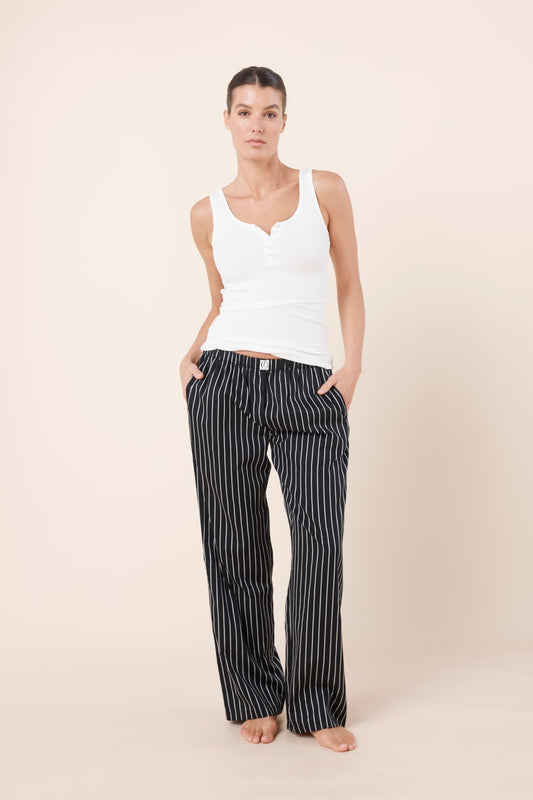 Woman wearing a white tank top and Willow Cotton Striped Pant Black on a beige background