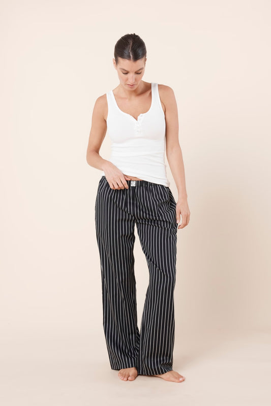 Woman wearing a white tank top and Willow Cotton Striped Pant in Black and white on a beige background