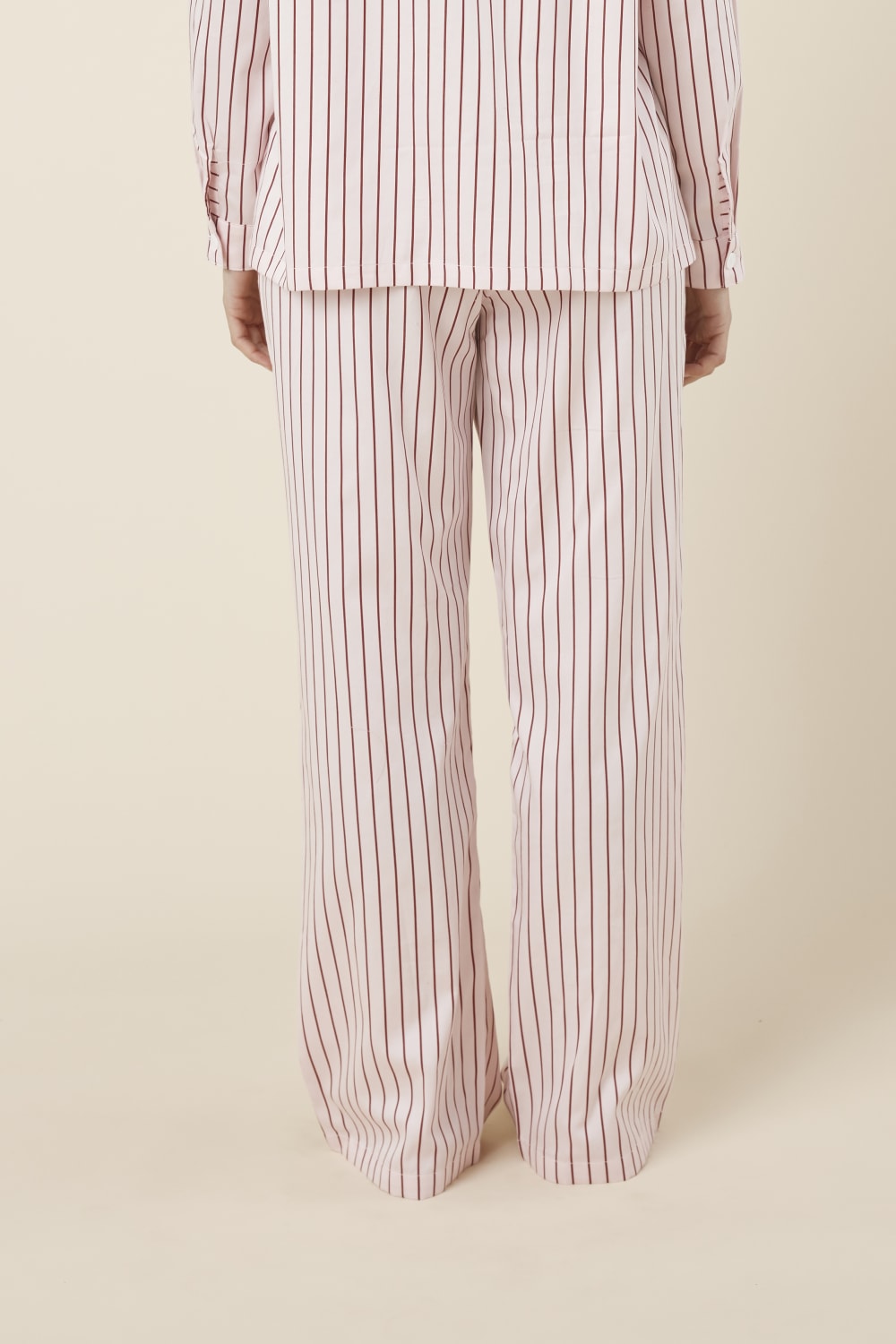 Person wearing willow cotton striped pant in pink and white stripe back view on a beige background
