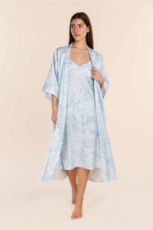 Woman wearing a light blue floral dress with a matching kimono-style cover-up on a beige background