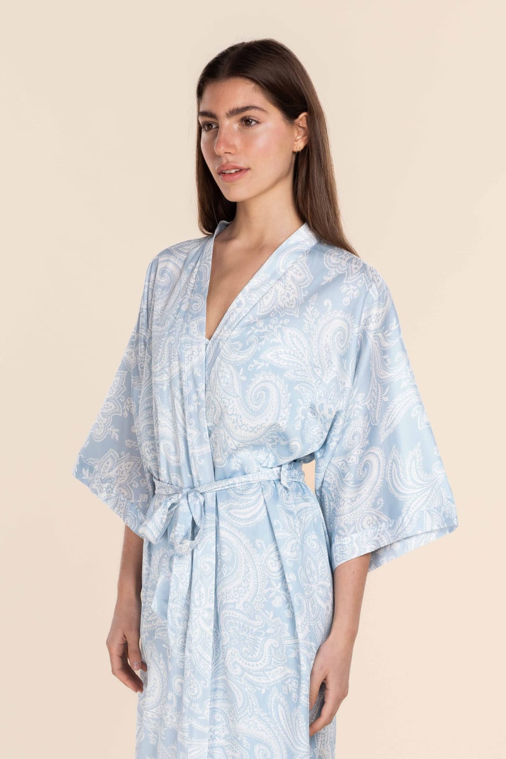 Woman wearing a light blue patterned robe against a beige background