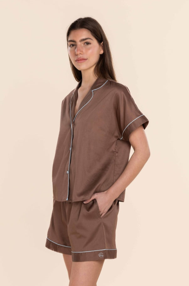 Woman wearing a brown pajama set on a beige background
