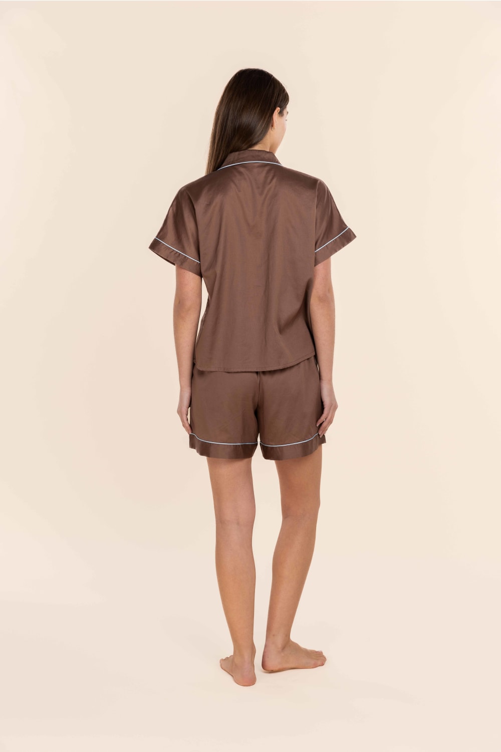 Woman wearing a brown pyjama set on a beige background