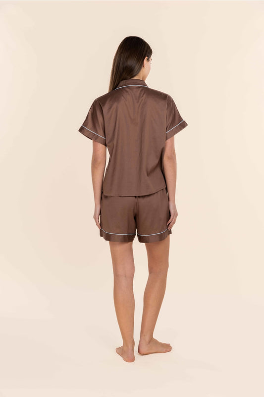 Woman wearing a brown pyjama set on a beige background