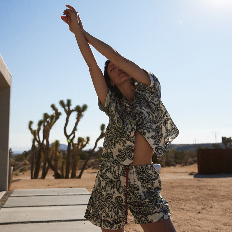 Person in a patterned outfit standing in a desert landscape with Joshua trees.