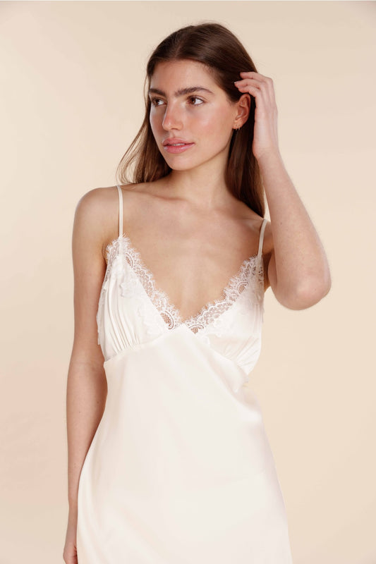 Woman wearing a white lace nightgown against a beige background