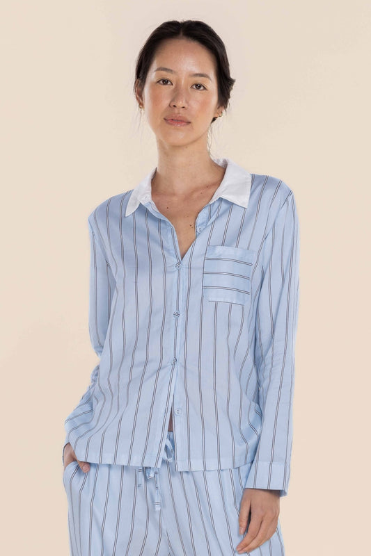 Woman wearing a light blue striped pajama set against a beige background
