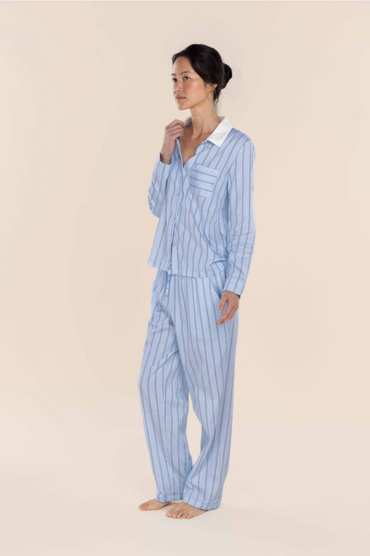 Woman wearing a light blue striped pajama set on a beige background
