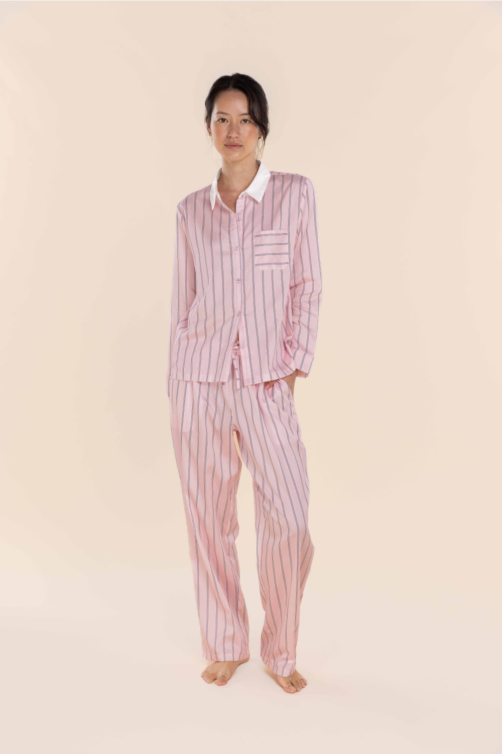 Person wearing a pink striped pajama set on a beige background