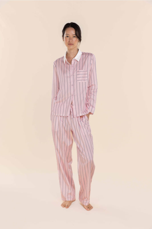 Person wearing a pink striped pajama set on a beige background