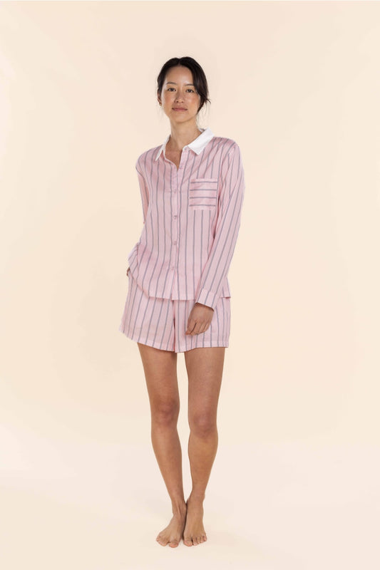 Woman wearing a pink and white striped pajama set on a beige background