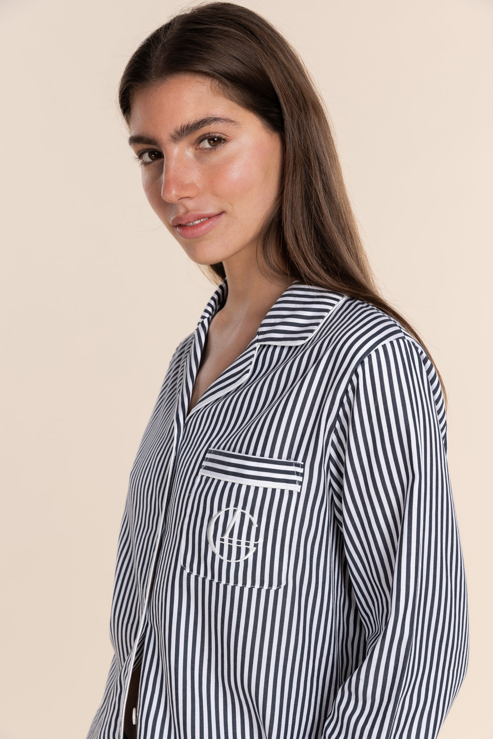 Woman wearing a black and white striped shirt with a logo on a beige background