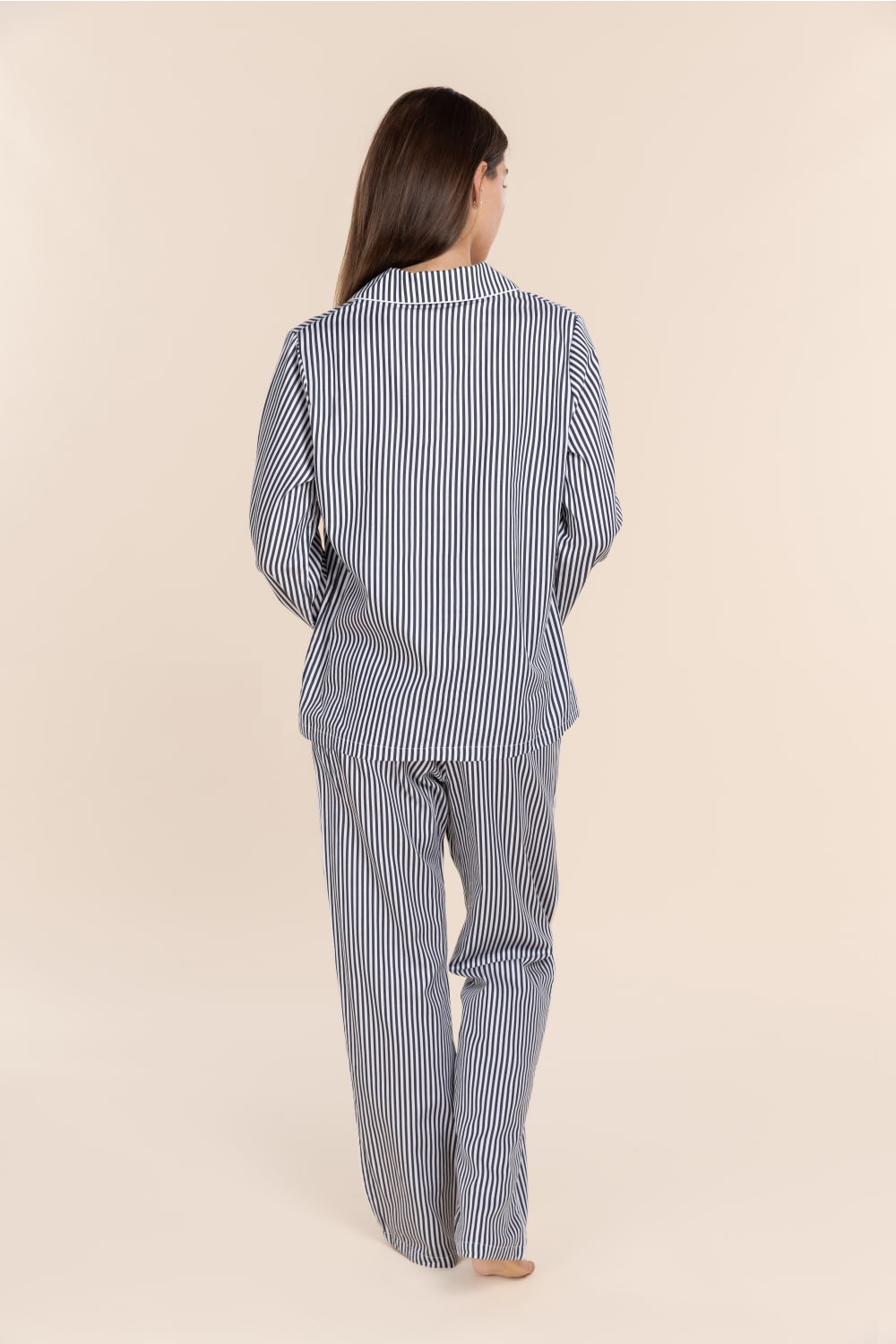 Person wearing a blue and white striped pajama set on a beige background