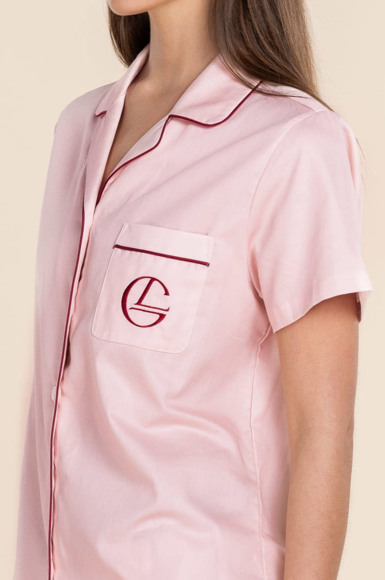 Pink satin pajama set with a logo on a beige background