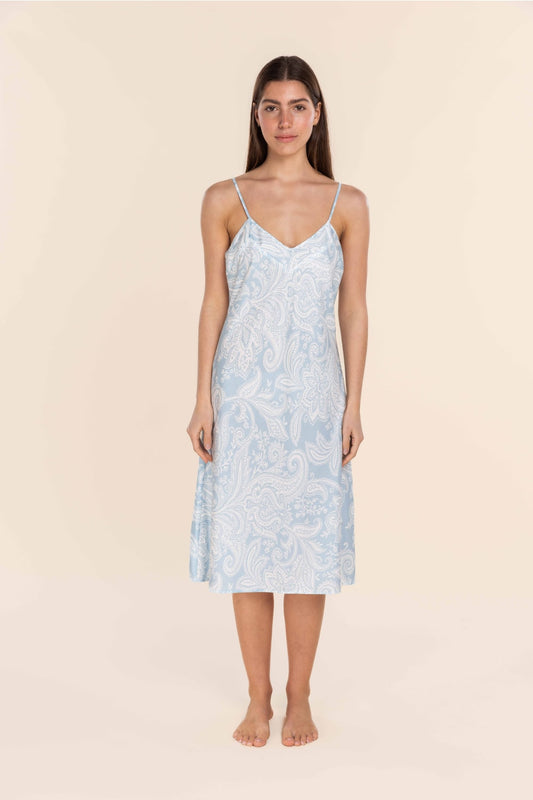 Woman wearing a light blue floral slip dress on a beige background