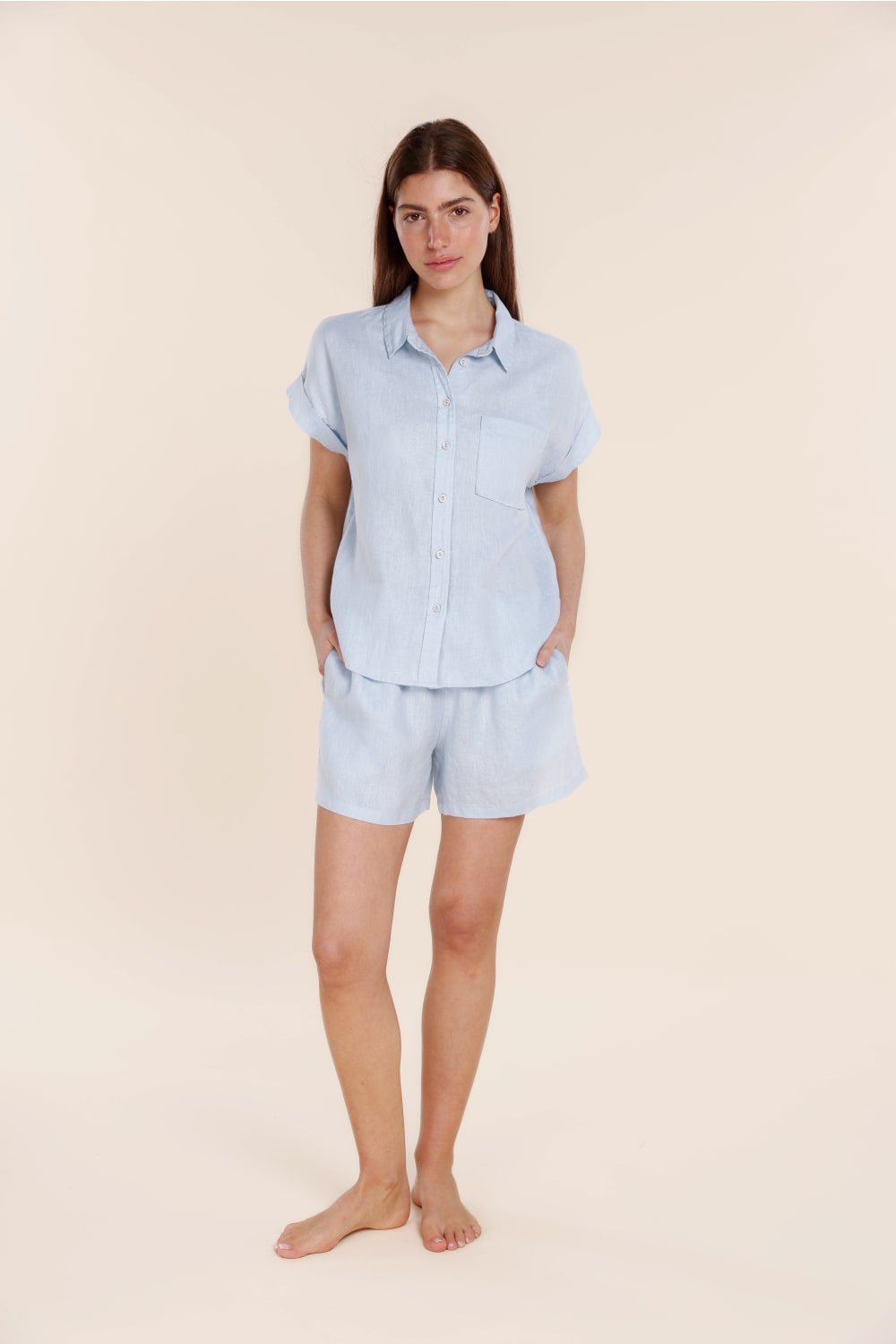 Woman wearing a light blue pajama set on a beige background