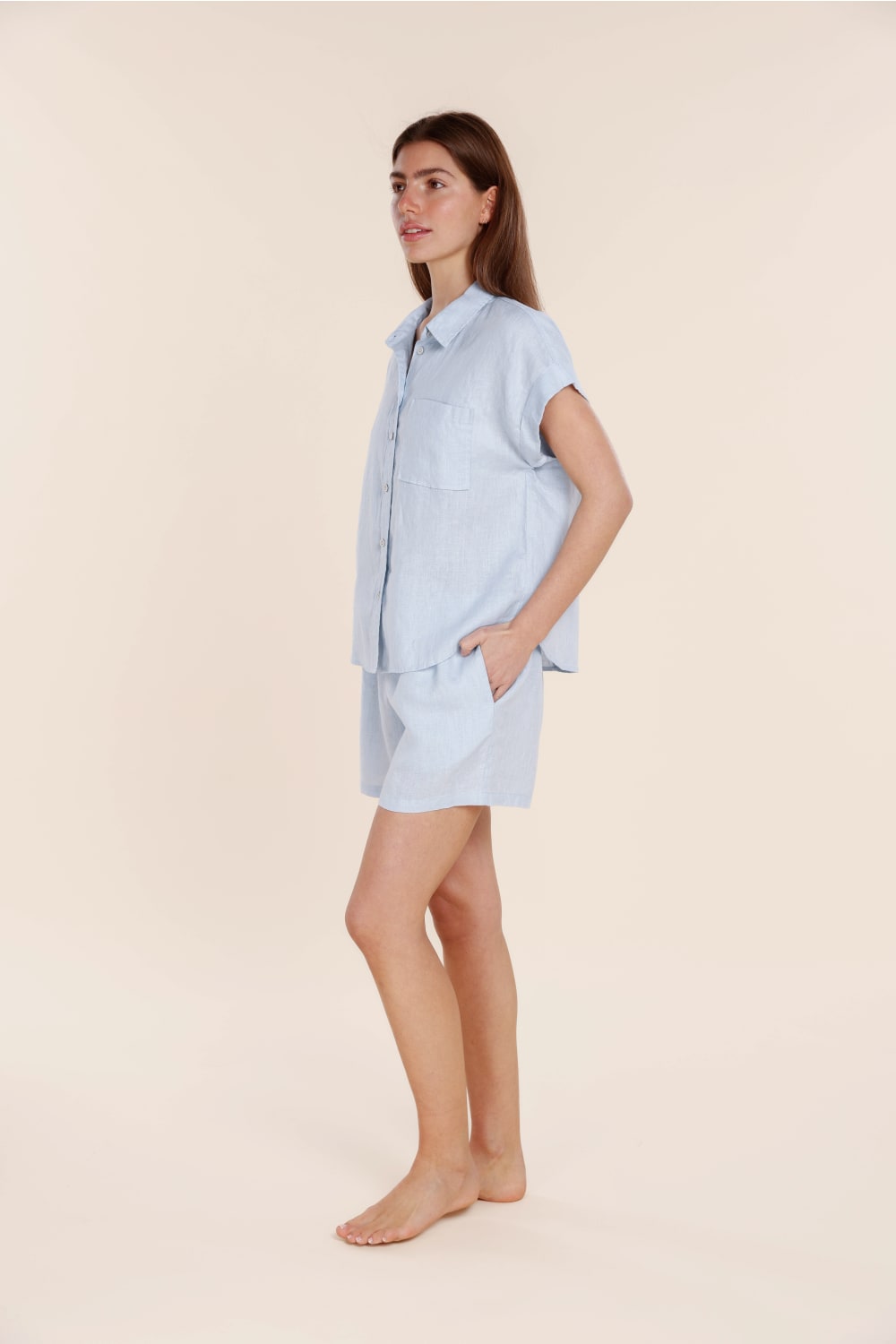 Woman wearing a light blue pajama set on a beige background