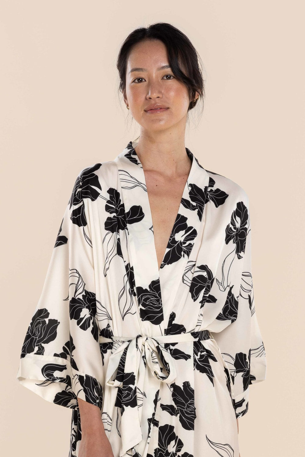 Woman wearing a black and white floral robe against a beige background