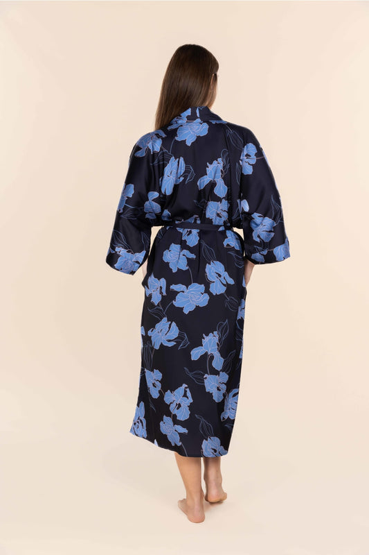 Woman wearing a navy blue robe with blue floral patterns on a beige background