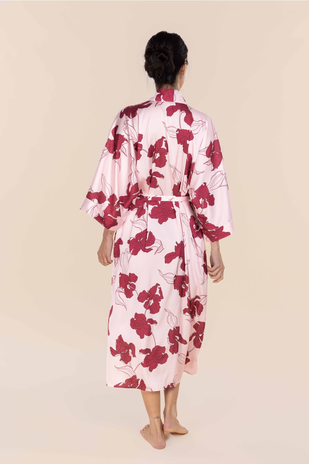 Woman wearing a pink floral robe against a beige background