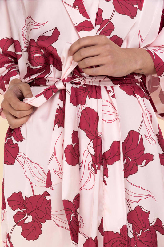 Close-up of a pink robe with red floral patterns, held by a person.