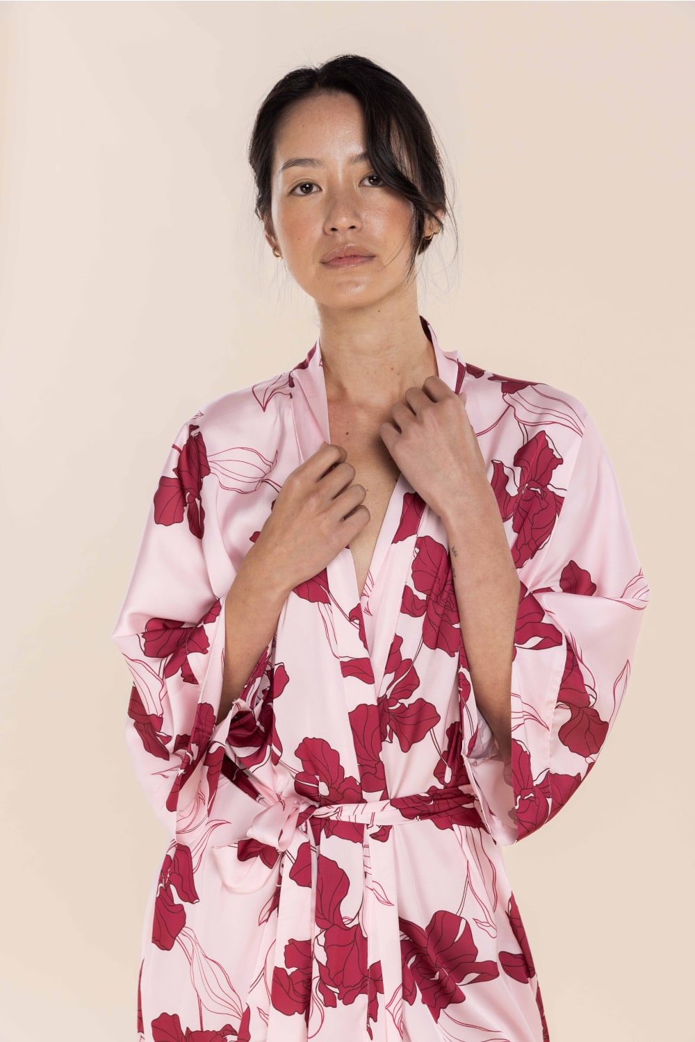 Woman wearing a pink floral robe against a beige background