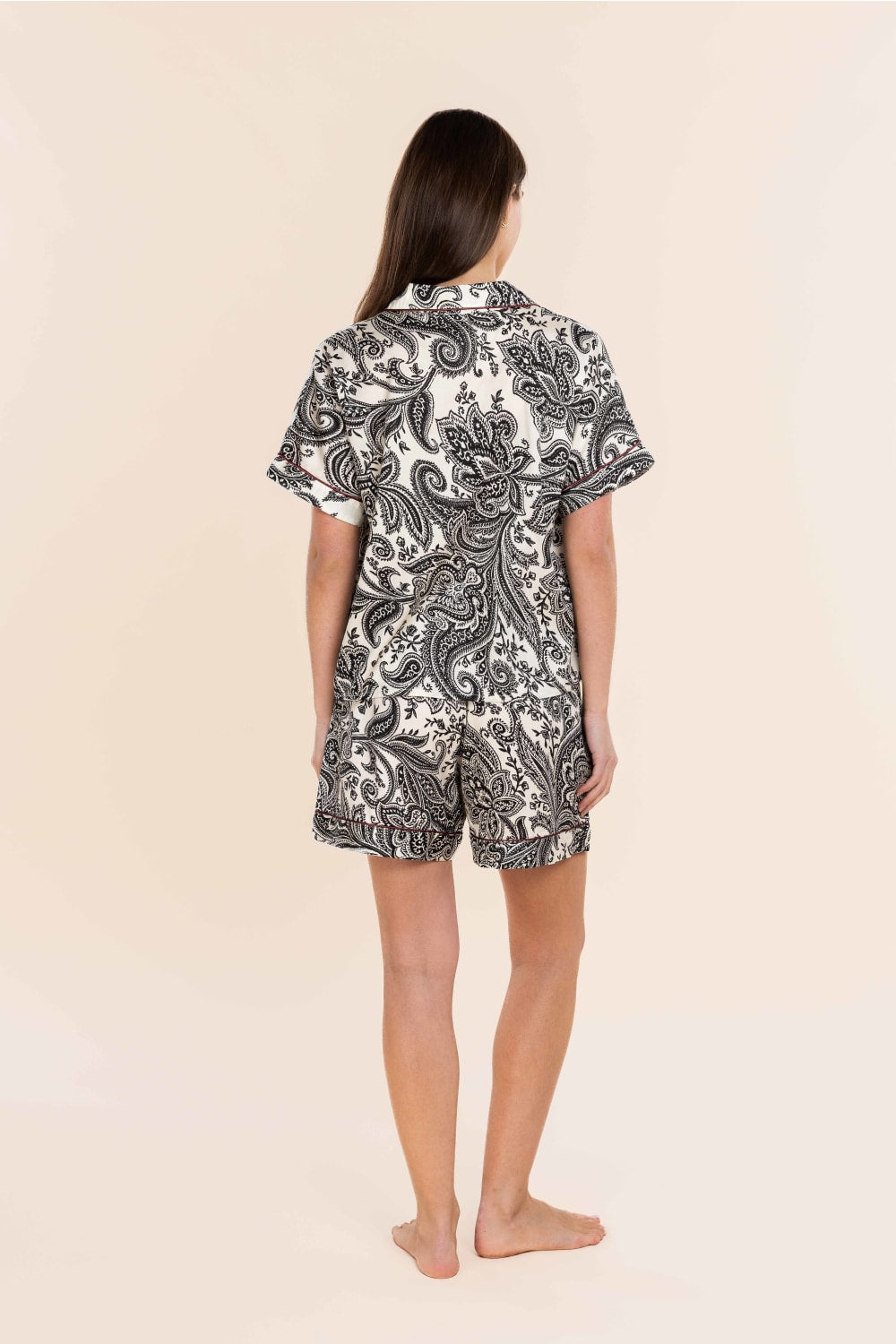 Person wearing a black and white patterned shirt and shorts set on a beige background