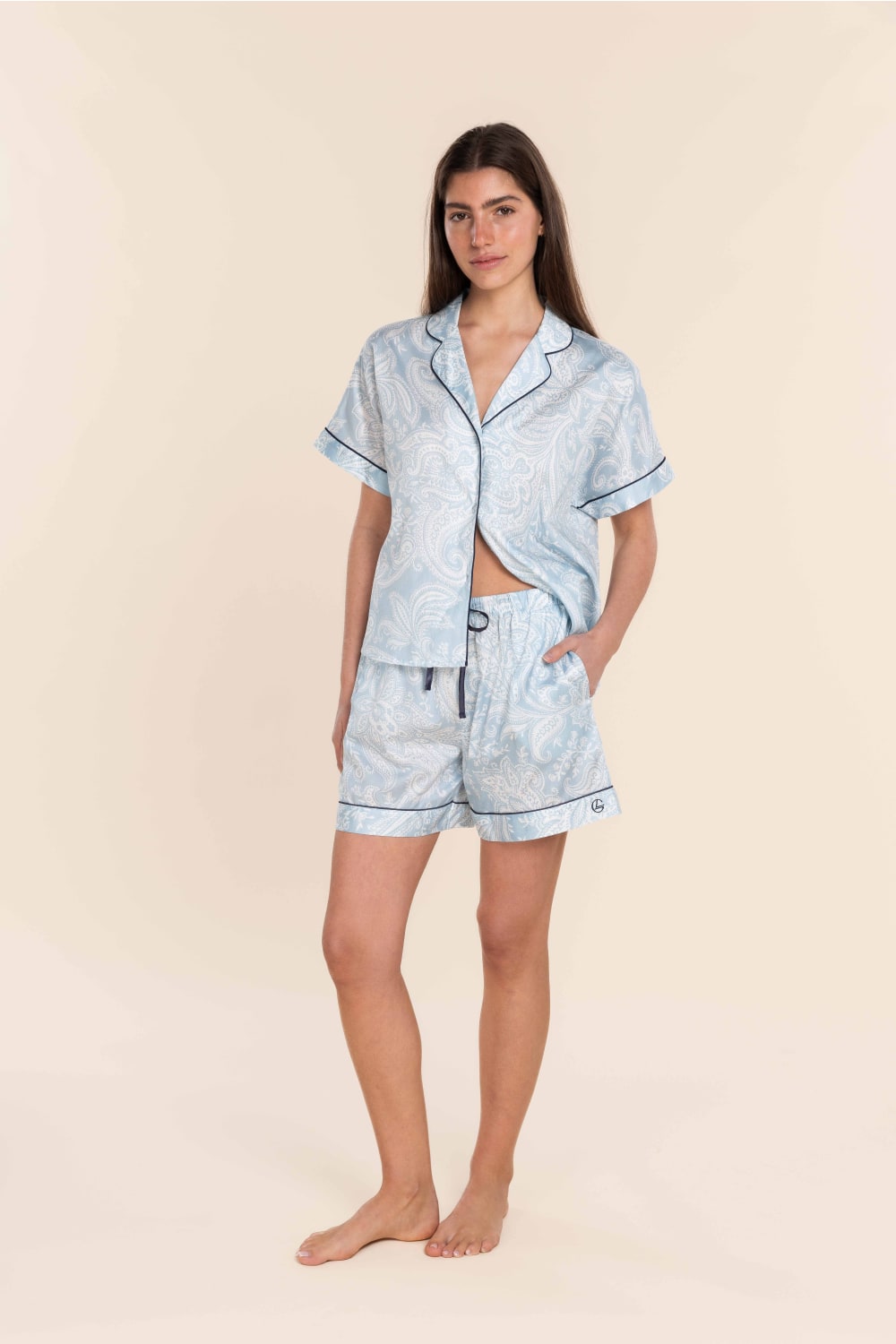 Woman wearing a light blue pajama set on a beige background