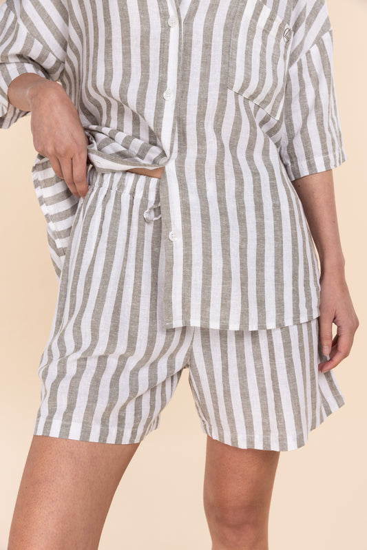 Person wearing a striped pajama set with shorts and a top on a beige background