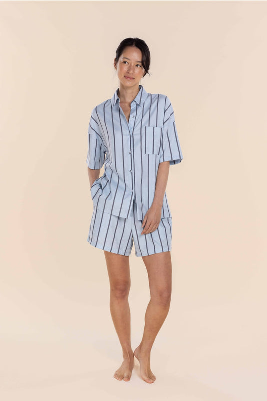 Woman wearing a blue and white striped pajama set on a beige background