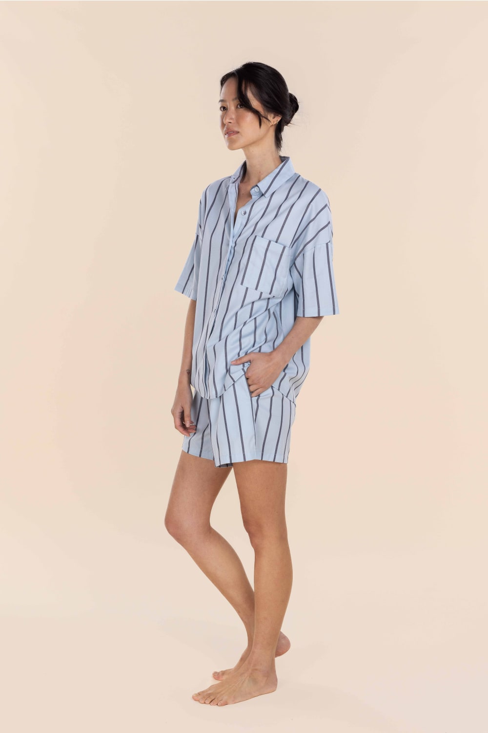 Woman wearing a blue and white striped pajama set on a beige background