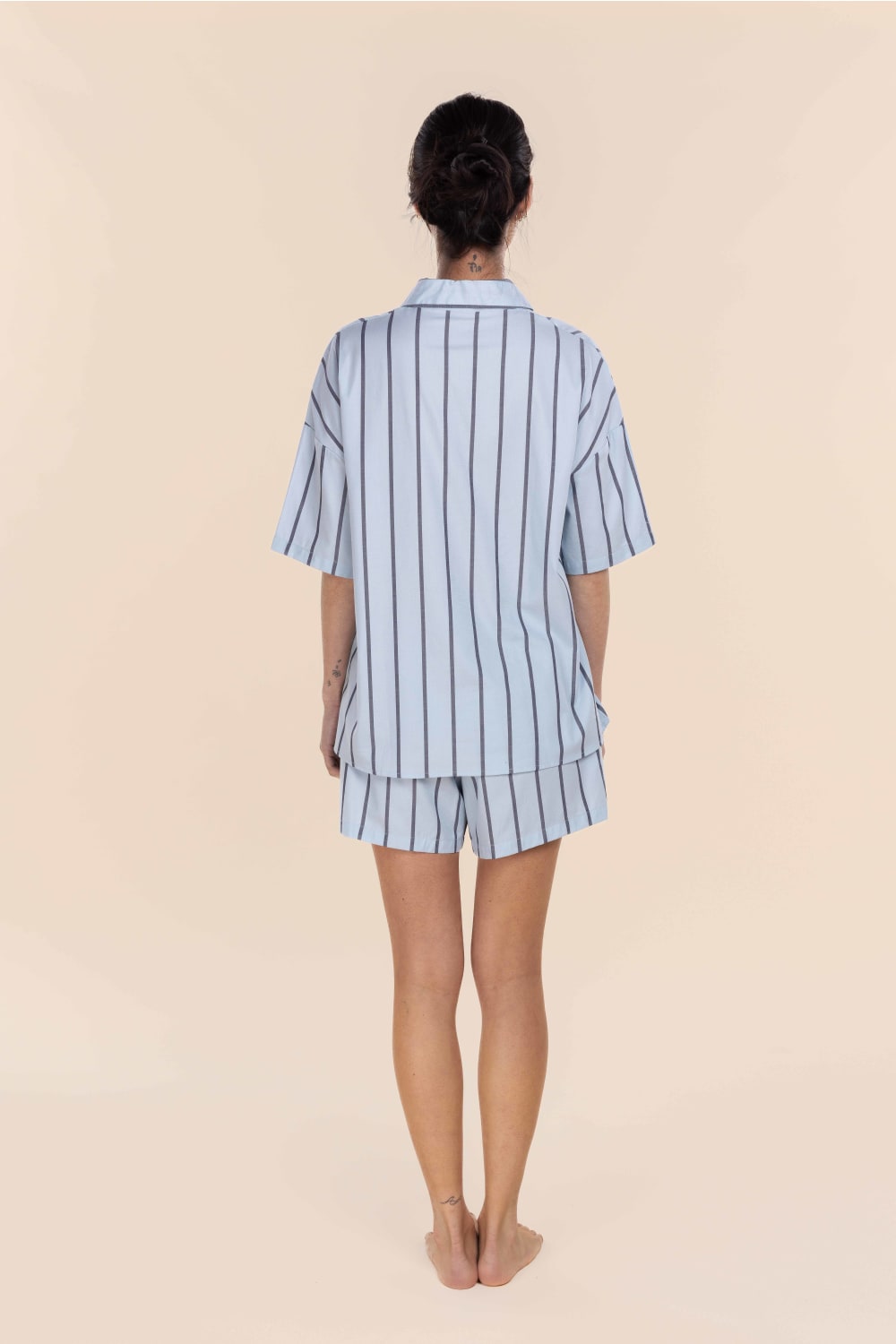 Person wearing a light blue and white striped pajama set on a beige background