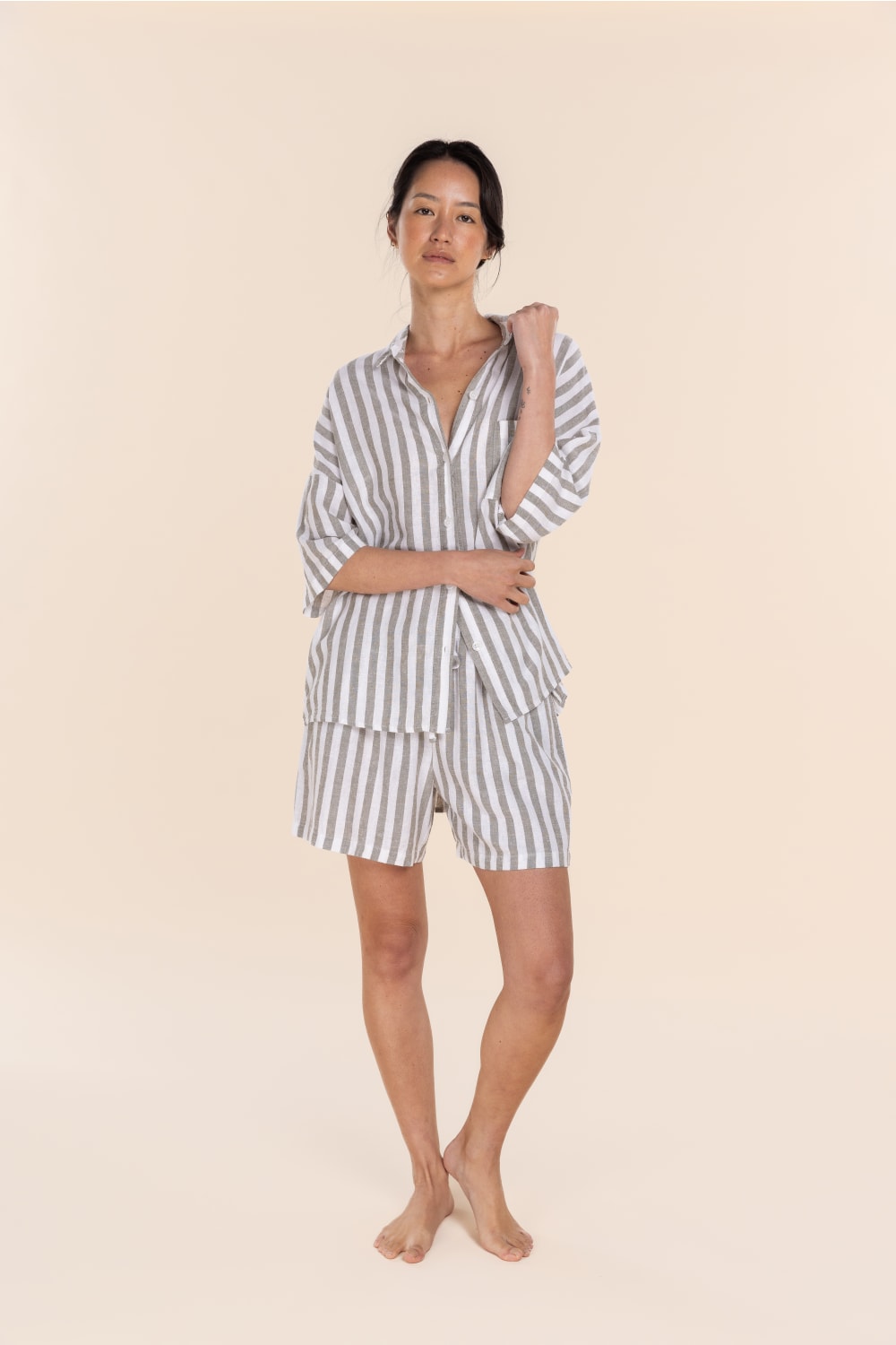 Woman wearing a striped pajama set on a beige background