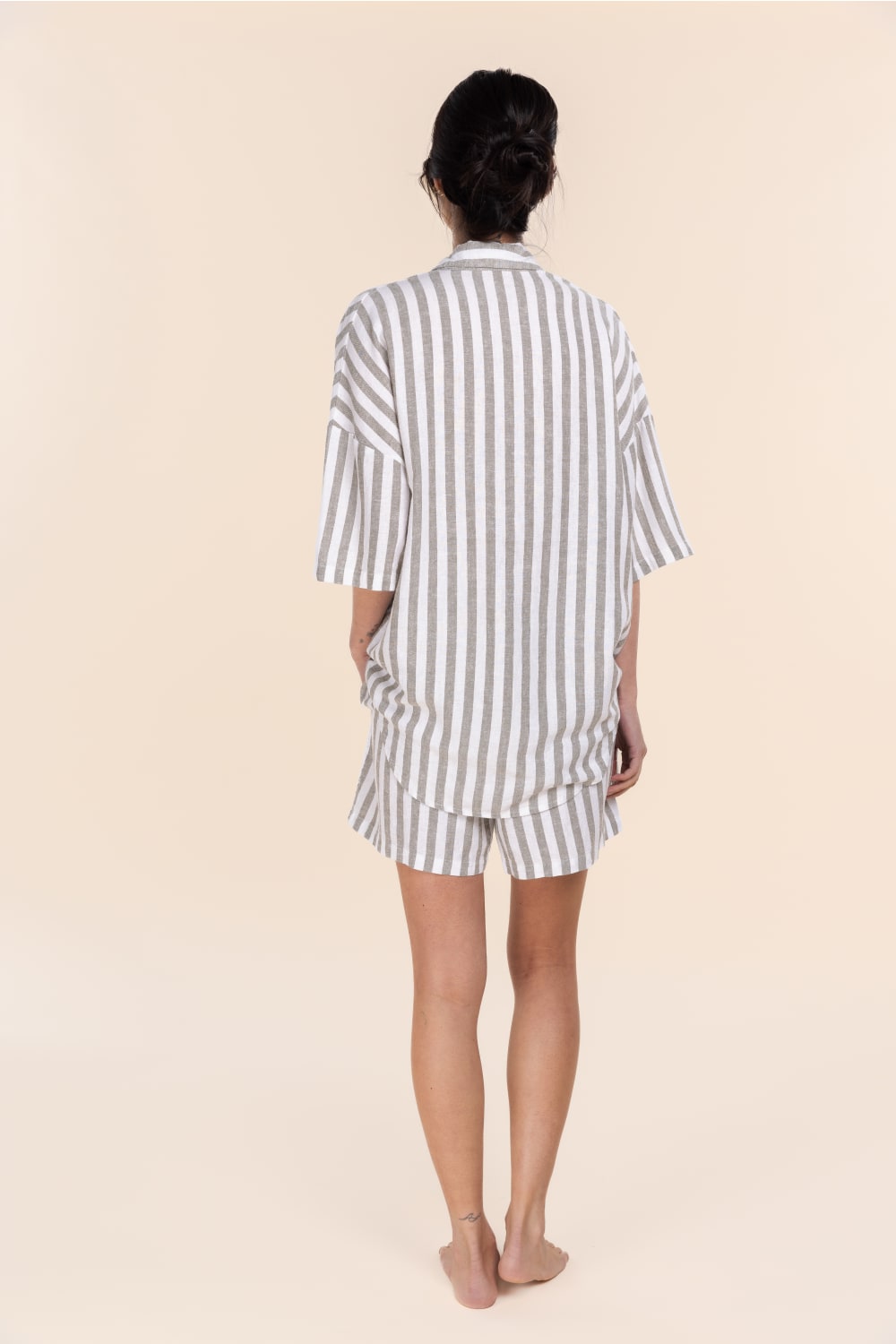 Person wearing a striped pajama set on a beige background