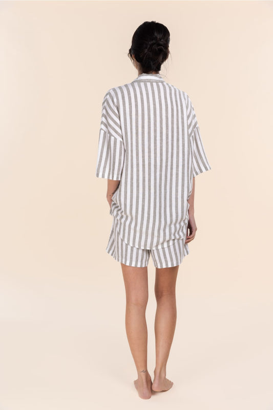 Person wearing a striped pajama set on a beige background