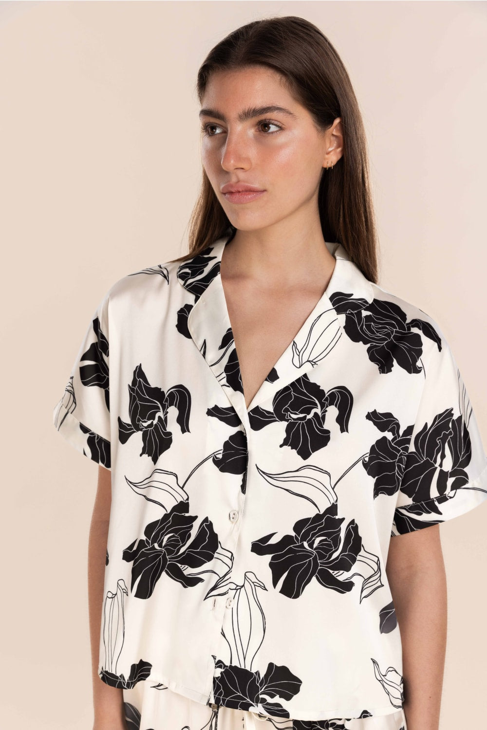 Woman wearing a white shirt with black floral patterns on a beige background