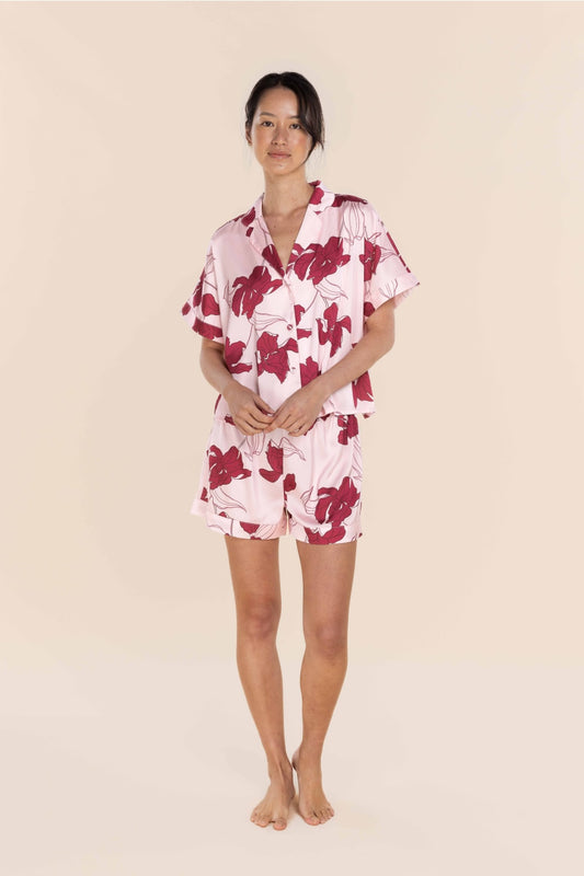 Woman wearing a pink floral pajama set on a beige background