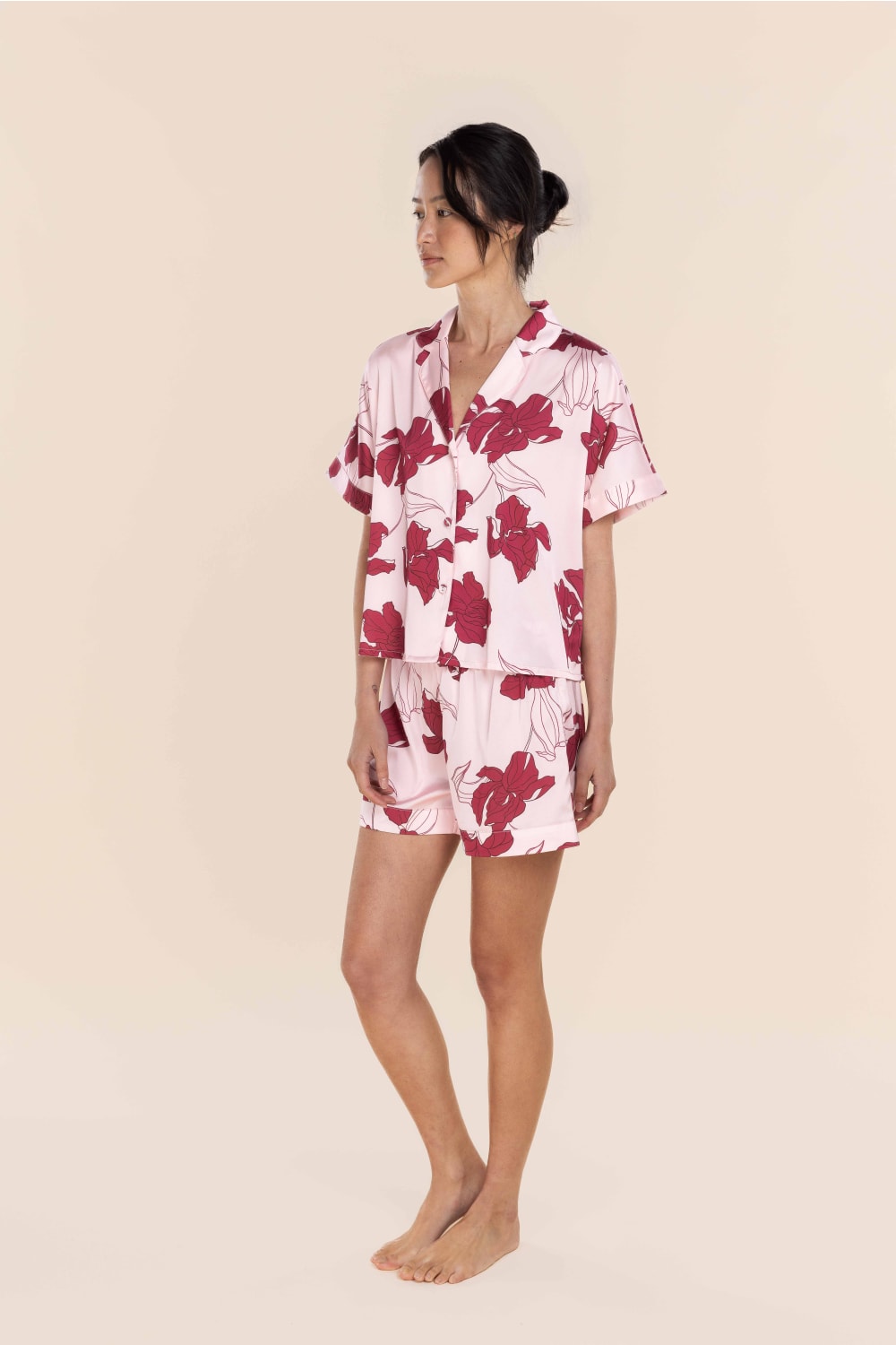 Woman wearing a pink floral pajama set on a beige background