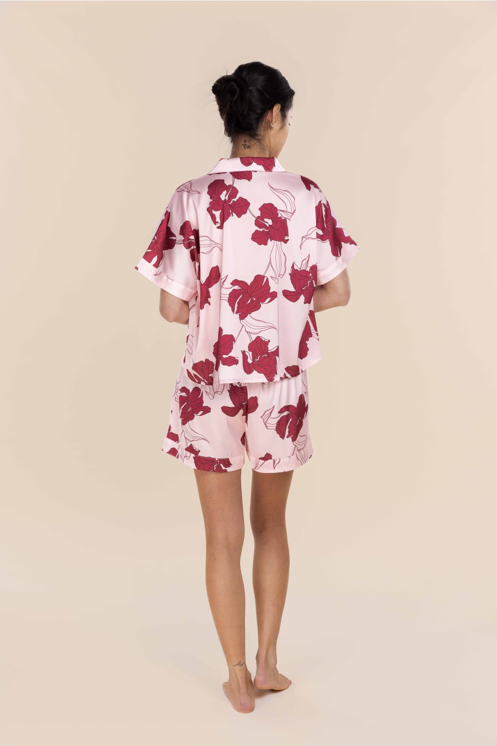 Woman wearing a pink floral pajama set on a beige background